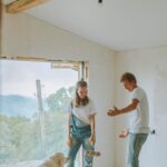 Dog resting in a room while people paint during a home renovation